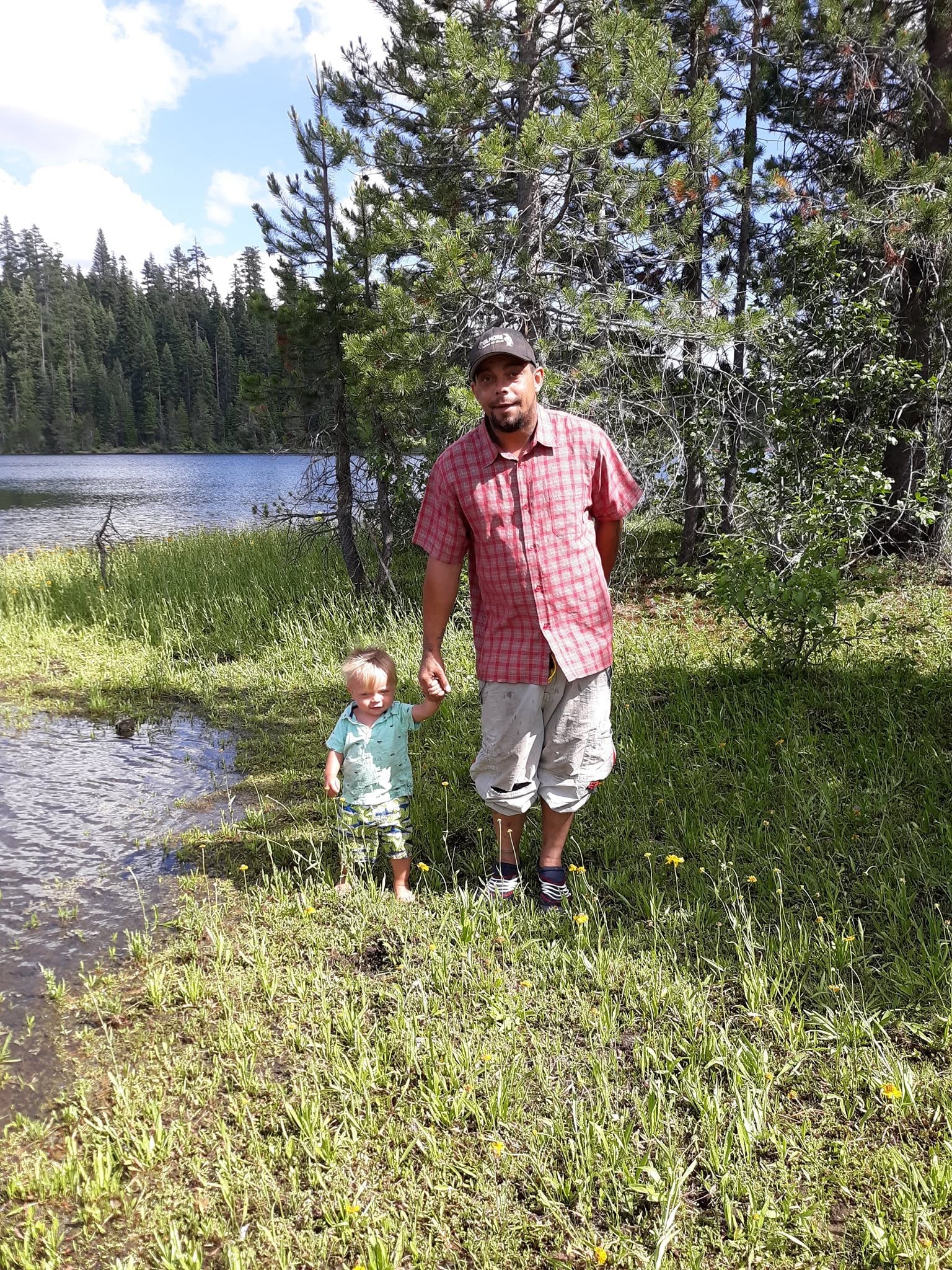 Adult and child walking beside a forest lake